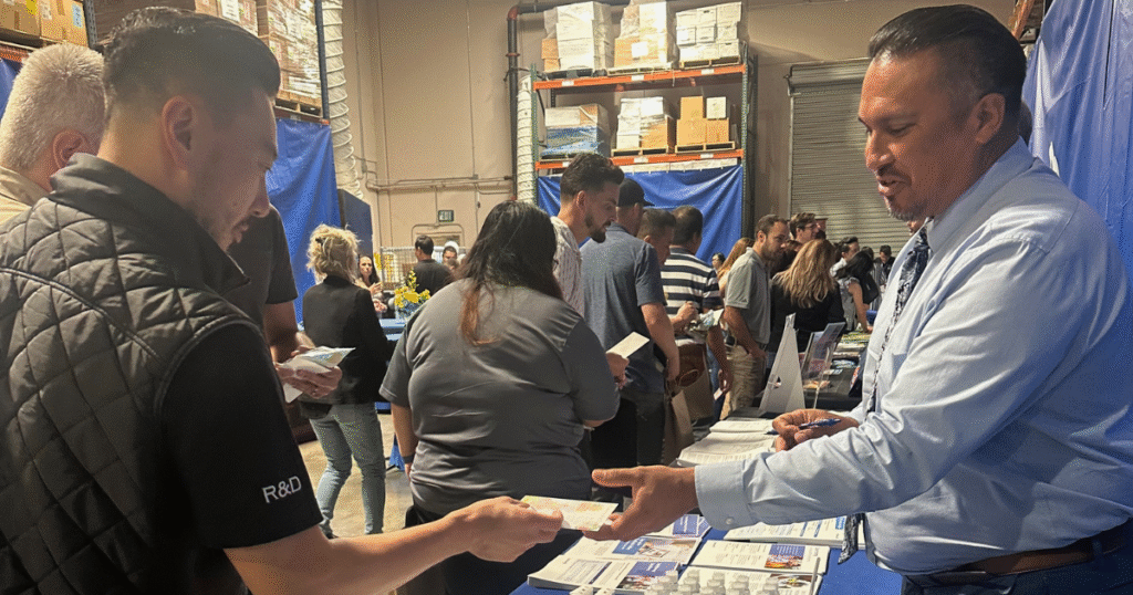 Exhibitor at a wellness fair engaging with an employee at a colorful, interactive booth