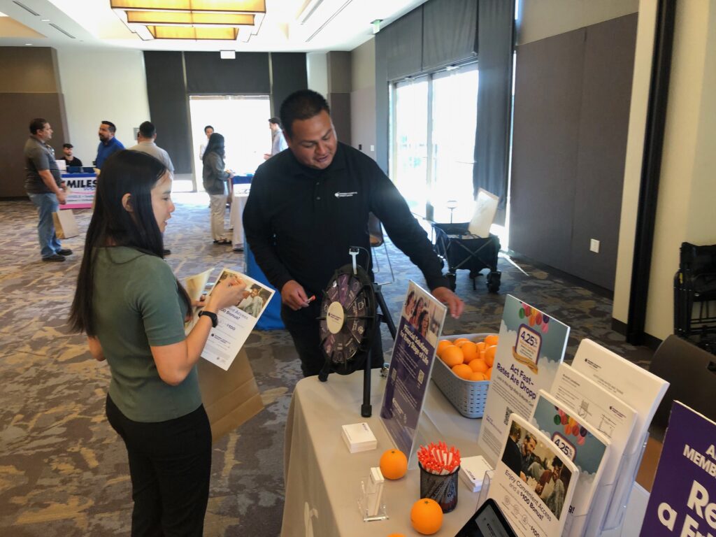 Employee engaging with a visitor at a wellness expo exhibitor booth